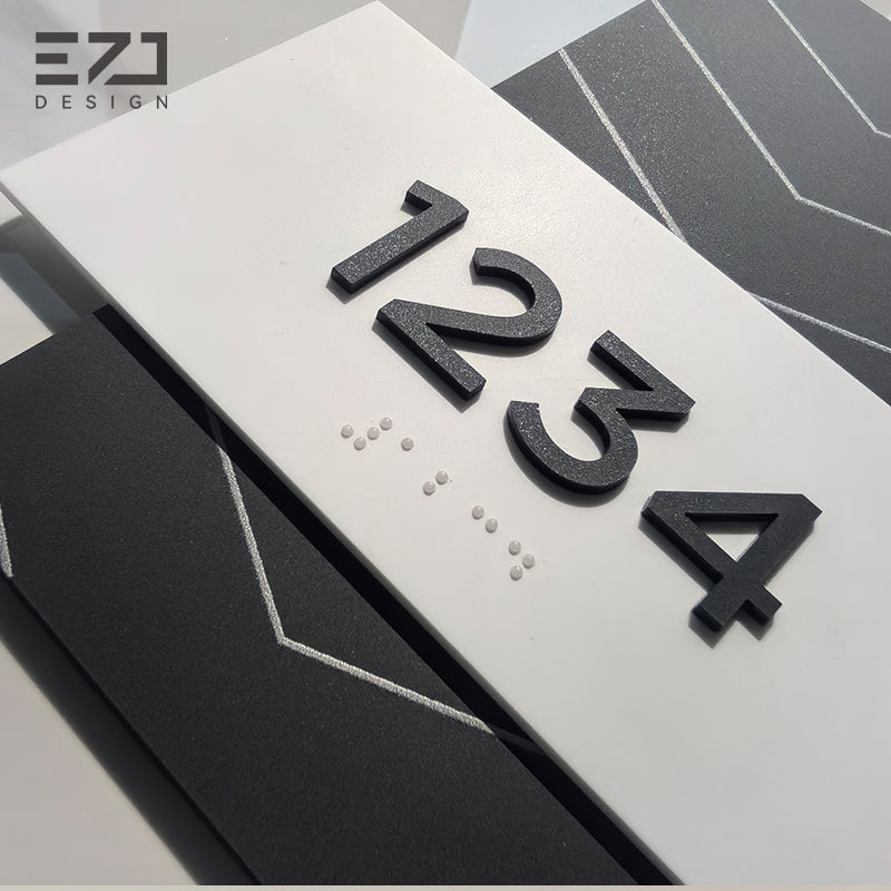 Close-up of raised black acrylic room numbers and Grade 2 Braille